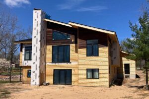 Large stained wood siding log home style building in the process of being sealed by Redemption Construction general contractor in Wisconsin Rapids