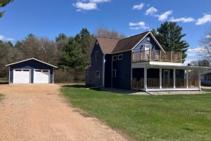 Redemption Construction general contractor in all things in home building and renovations has over 40 years experience in custom built decking and home in blue vinyl siding with garage doors in white